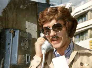 Жорж Милославский в телефонной будке разговаривает по телефону.