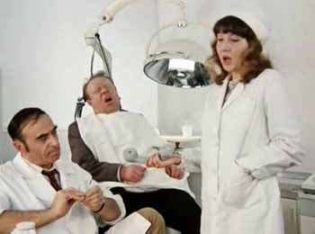 Медсестра передает телефонную трубку стоматологу Шпаку. Пациент ждет своих мучений в зубоврачебном кресле.
